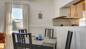 A dining area with a table, chairs, a vase, and a window with curtains. - Oakland Apt on Messalonskee Lake w/ Dock Access! (Oakland)