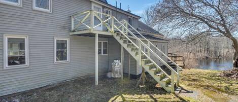 Una casa de dos pisos con una escalera de madera que lleva a la puerta principal.