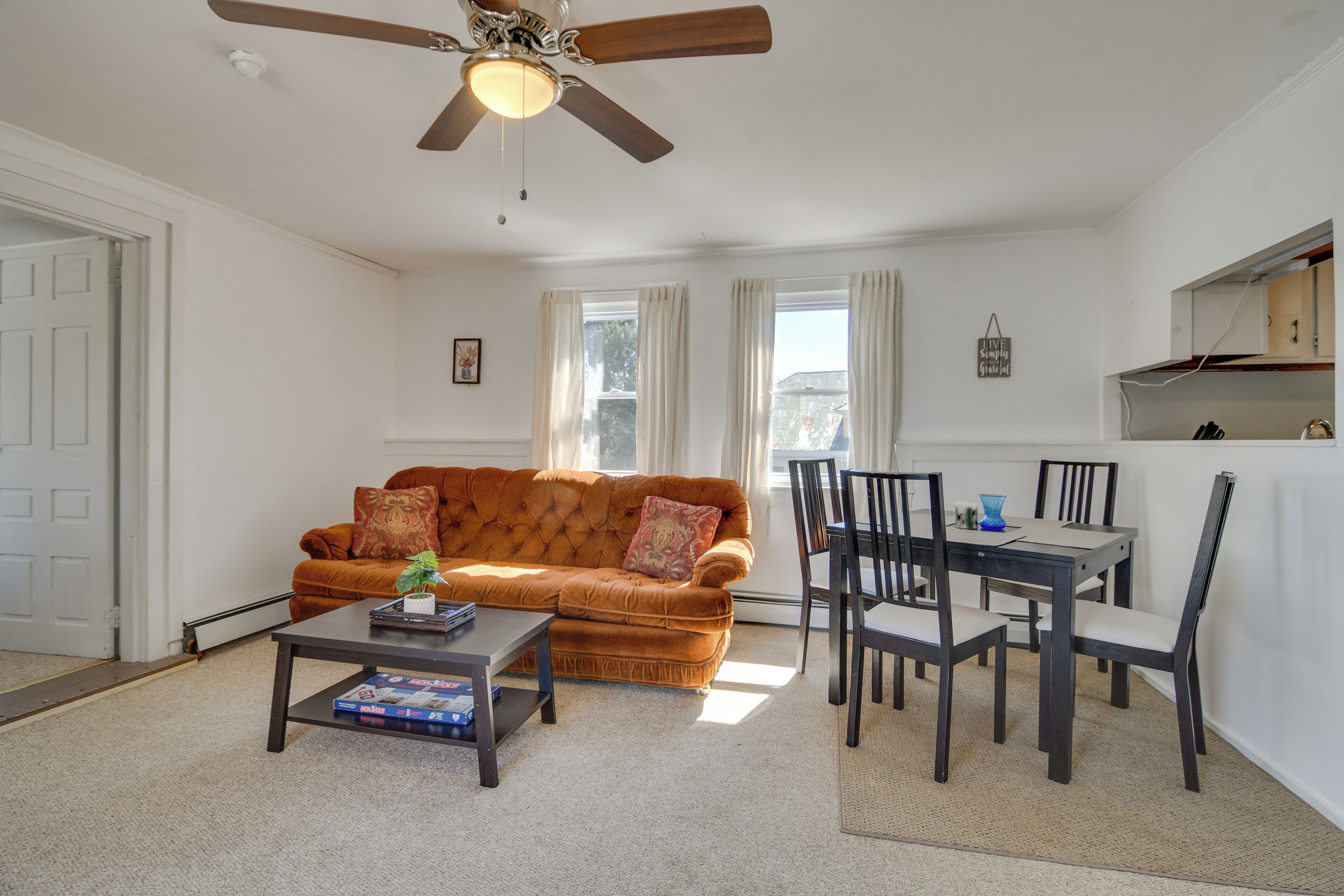 A living room with a brown sofa, a coffee table, and a dining table with chairs.
