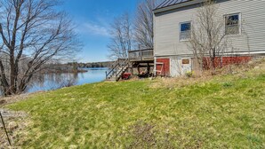 A house with a dock extending into a lake, surrounded by trees and a grassy area. - Lakefront Oakland Vacation Rental w/ Dock + Views! (Oakland)