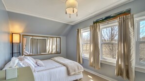 A bedroom with a large bed, a bedside table, a mirror, and a window with curtains. - Lakefront Oakland Vacation Rental w/ Dock + Views! (Oakland)