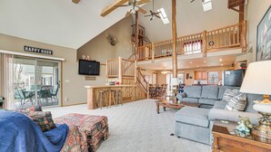 A spacious living area with a high ceiling, wooden staircase, and a cozy seating area. - Family-friendly Houghton Lake House: Steps to Lake (Houghton Lake)