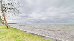 A riverside walkway with a grassy area and a tree. - Family-friendly Houghton Lake House: Steps to Lake (Houghton Lake)