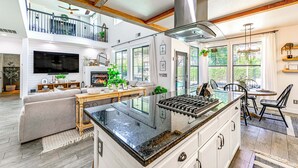 Una cocina amplia con una isla grande, un comedor con mesa redonda y una sala de estar con sofá y chimenea.