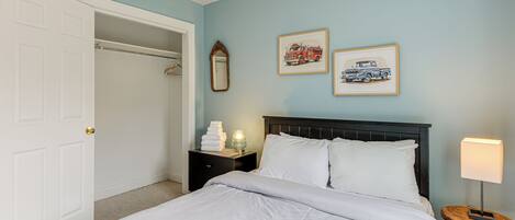 Un dormitorio con una cama, mesitas de noche, un espejo y cuadros en la pared.