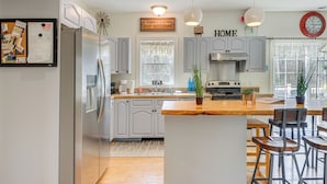 Une cuisine moderne avec des meubles gris, des appareils en acier inoxydable et un îlot central en bois doté de tabourets de bar.