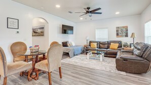 A spacious living room with a glass dining table, leather sofas, and a ceiling fan. - Pensacola Home on 1 Acre w/ Large Yard & Grill! (Pensacola)