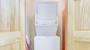 Eine weiße Waschmaschine und ein Trockner in einem Hauswirtschaftsraum mit Holzausbau.