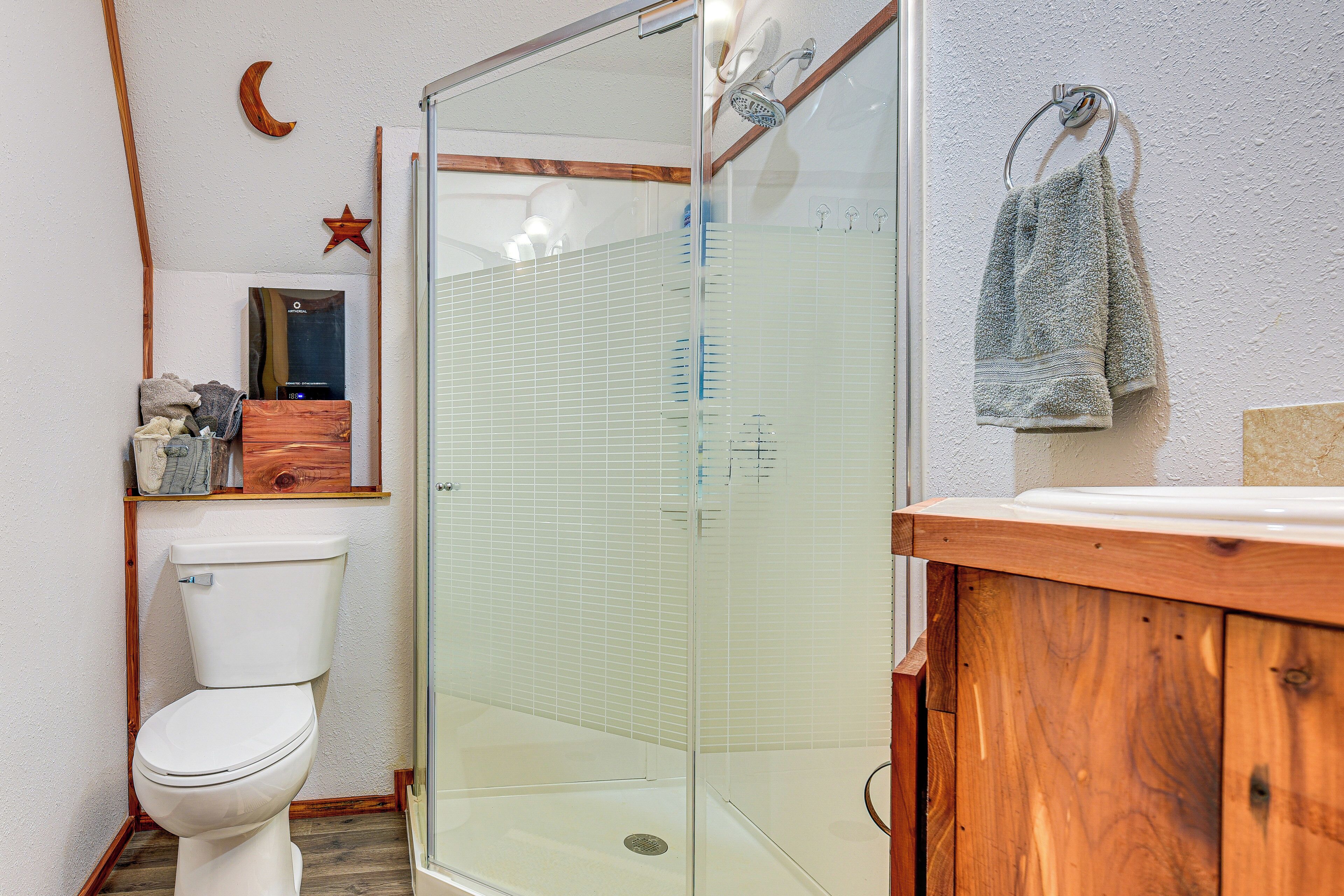 A bathroom with a toilet, a glass shower enclosure, and a wooden vanity.