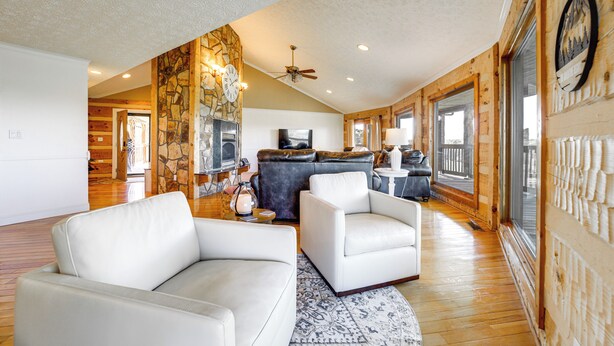 A spacious living room with a fireplace, a stone accent wall, and a large window.