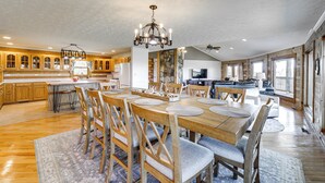 A spacious kitchen with wooden cabinets, a dining area with a large wooden table and chairs, and a chandelier.