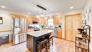 A modern kitchen with wooden cabinets, stainless steel appliances, and a central island with stools. - Pocono Lake House Hideaway: Hot Tub & Theater Room (Pocono Lake)