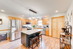 A modern kitchen with stainless steel appliances, wooden cabinets, and a central island with bar stools.