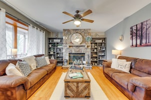 A living room with two brown leather sofas, a coffee table, a stone fireplace, and a ceiling fan.