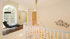 Un intérieur spacieux avec un plafond haut, une balustrade blanche et un escalier menant à un niveau supérieur.