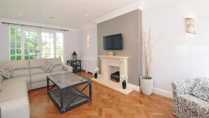 Un salon avec une cheminée, un canapé, une table basse et un téléviseur fixé au mur.