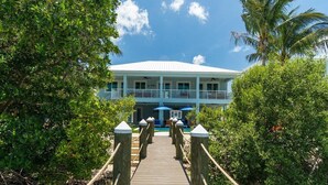A wooden bridge leading to a building with a white roof and blue accents. - Seaside Serenity~ Luxury Waterfront Pool Home w/ 35` Dock (Marathon)