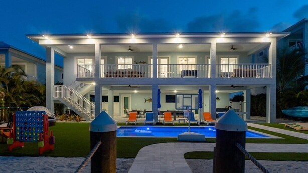 A two-story house with a swimming pool, a covered patio, and a staircase leading to the upper floor. - Seaside Serenity~ Luxury Waterfront Pool Home w/ 35` Dock (Marathon)