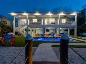 A two-story house with a swimming pool, a covered patio, and a staircase leading to the upper floor. - Seaside Serenity~ Luxury Waterfront Pool Home w/ 35` Dock (Marathon)