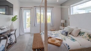 Ein Schlafzimmer mit einem Himmelbett, einem Schreibtisch mit Stuhl und einem großen Fenster.