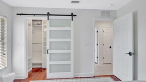 A bedroom with a sliding door closet, a white toilet, and a wooden floor. - 5BR Marco Island Home | Pool & Hot Tub (Marco Island)