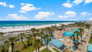 Un complexe hôtelier de bord de mer doté d’une piscine, d’une plage et de palmiers.
