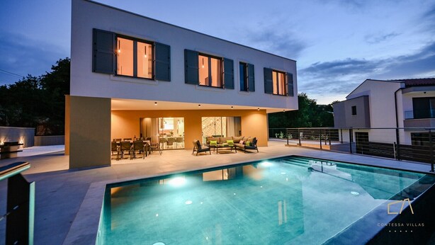 A modern two-story house with a swimming pool, outdoor dining area, and a well-lit interior. - Luxury Villa Brajdini (Vrbnik)