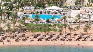 Un resort con una grande piscina, palme e ombrelloni sulla spiaggia.