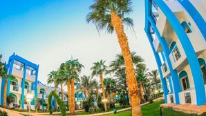 Un hotel dall'architettura bianca e azzurra, con palme e un giardino curato.