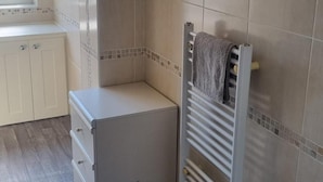 Ett litet, avskilt badrum med en handduksställning, ett element och ett skåp.