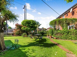 Un cortile residenziale con tavolo da picnic, un albero e una casa in mattoni.