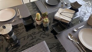 A dining table with a black marble top, surrounded by chairs, and various dining items including plates, cutlery, and a small cactus plant. - Casa vacanza a due passi dal mare, centralissima, ristrutturata (Terracina)