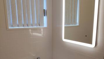 Tweepersoonskamer | Badkamer | Een douche, een haardroger, handdoeken, zeep