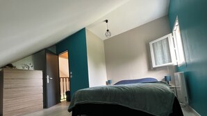 A bedroom with a bed, a dresser, a desk, and a window.
