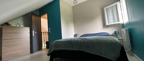 A bedroom with a bed, a dresser, a desk, and a window.