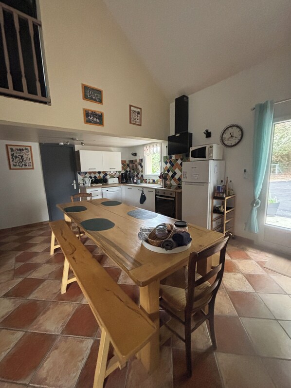 A kitchen with a wooden table, benches, and a refrigerator.
