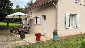 A house with a patio area, outdoor furniture, and potted plants.