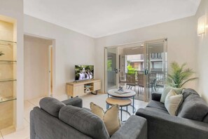 A modern living room with a sofa, TV, and a small table.