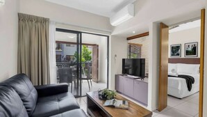 A modern living room with a sofa, coffee table, TV, and sliding glass doors leading to a balcony.