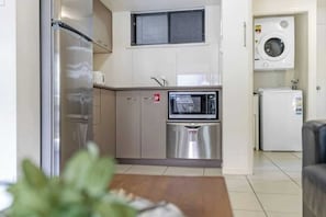 A compact kitchen with a stainless steel refrigerator, a microwave, and a built-in oven.