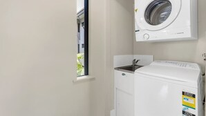 A laundry room with a washing machine, a dryer, and a window.