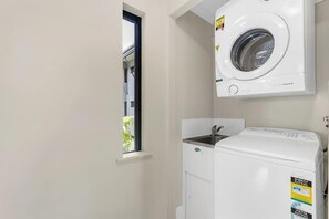 A laundry room with a washing machine, a dryer, and a window.