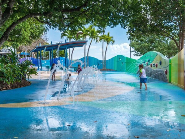Un espace de jeux aquatiques doté de plusieurs jets d’eau et d’un espace de repos abrité.