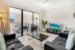 Un soggiorno moderno con una porta vetrata che dà su un balcone, una TV a schermo piatto e un tavolino da caffè.
