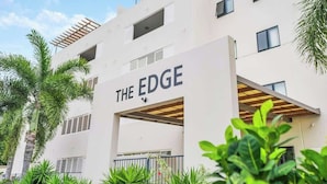 Un edificio moderno con la señalización 'THE EDGE', que presenta una fachada plana, múltiples ventanas y un área de entrada cubierta.