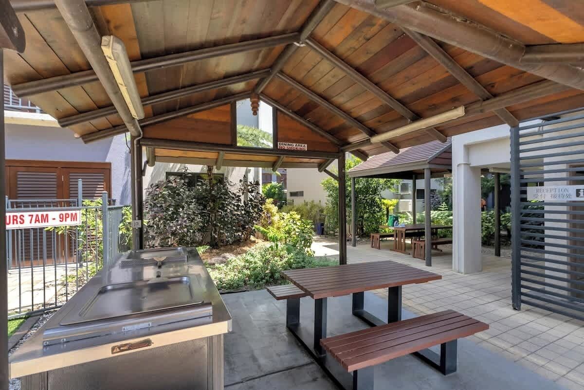 An outdoor dining area with a covered roof, a grill station, and a reception area.