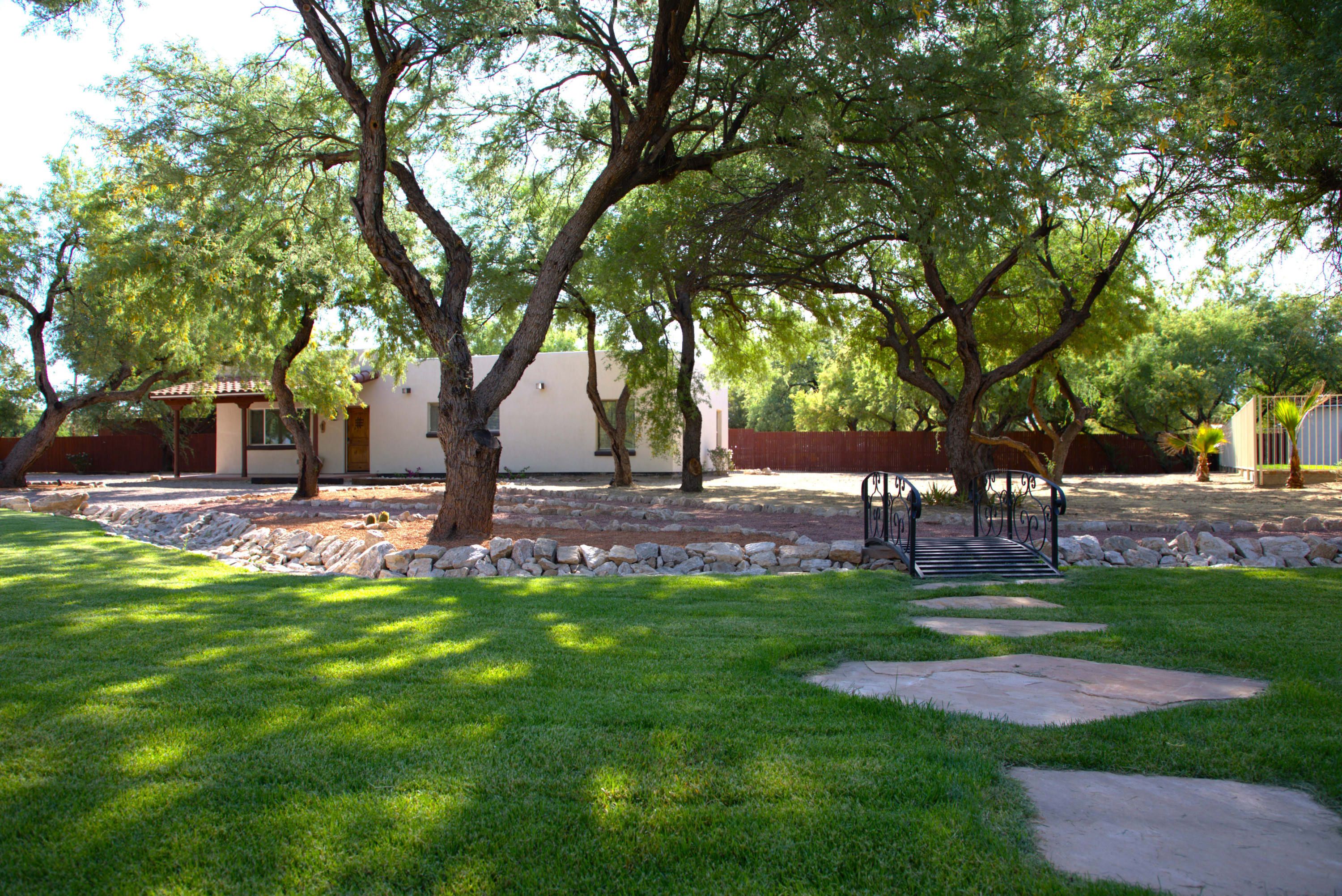 A well-maintained outdoor area with a stone pathway, a bench, and mature trees providing shade.