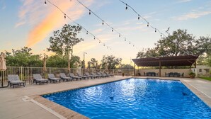 A swimming pool with lounge chairs and string lights, surrounded by trees and a covered seating area. - Large 4BR Villa Near Heated Pool | Solana 1 (Tucson)