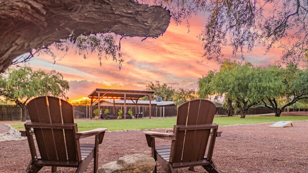 Two Adirondack chairs facing a covered patio with a view of a sunset. - Large 4BR Villa Near Heated Pool | Solana 1 (Tucson)