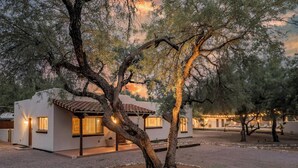 A modern building with a white exterior and a tiled roof, surrounded by trees and a gravel courtyard. - Large 4BR Villa Near Heated Pool | Solana 1 (Tucson)